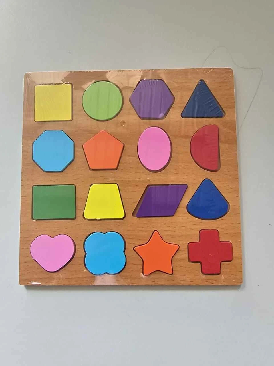 Wooden puzzle with colorful geometric shapes on a plain background