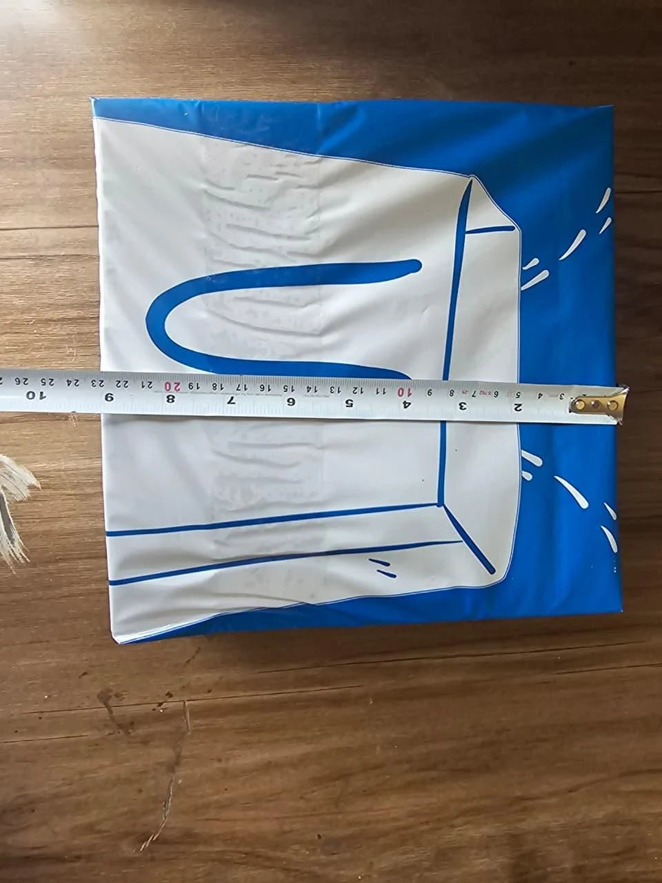 White fabric with blue designs on a wooden surface, measured by a ruler.