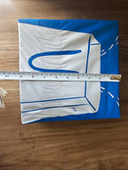 White fabric with blue designs on a wooden surface, measured by a ruler.