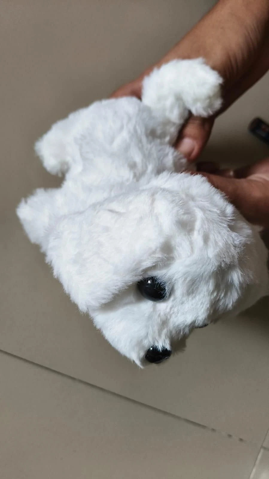 White plush toy resembling a dog held by a hand on a neutral background