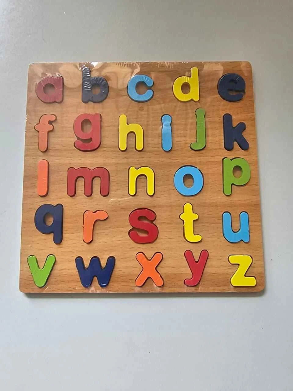 Wooden alphabet puzzle with colorful letters on a plain background