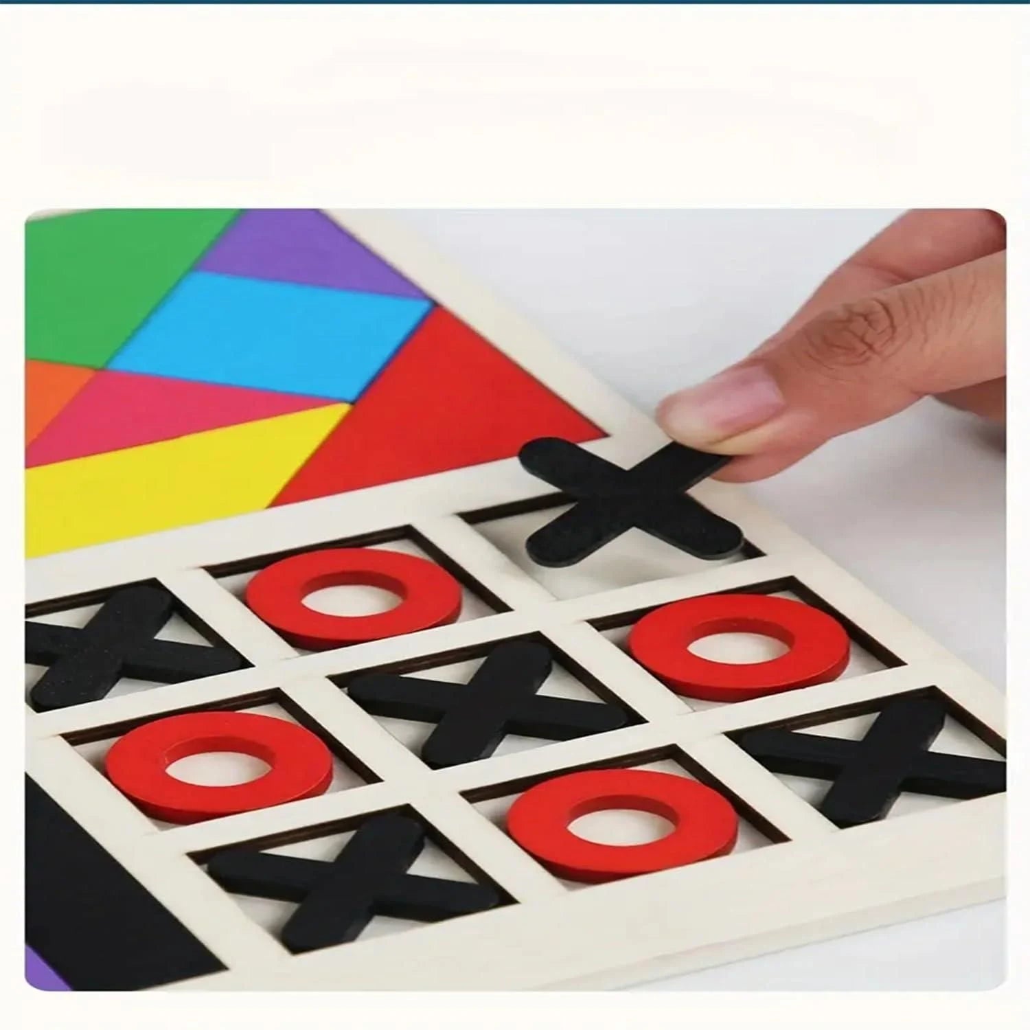 Colorful geometric shapes on a board with a hand placing an 'X' piece.